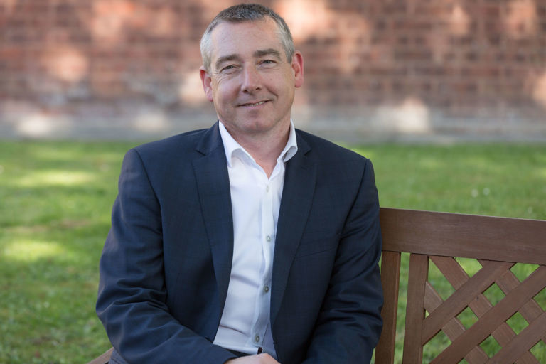 Man in suit sitting on a wooden bench in a garden Man in suit sitting on a wooden bench in a garden