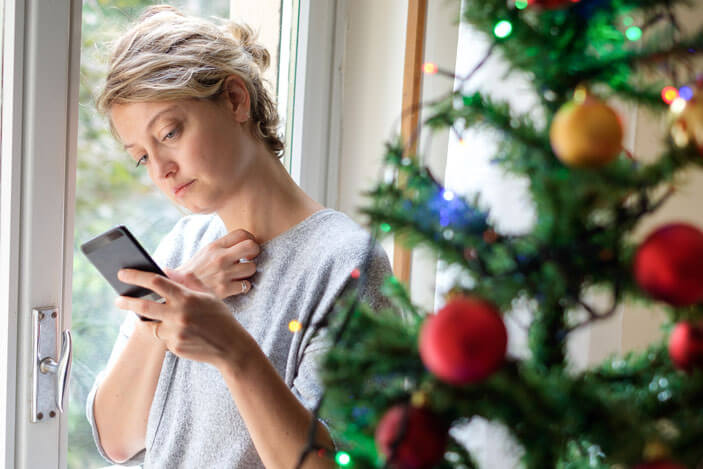 lady looking at her phone in front of a Christmas tree