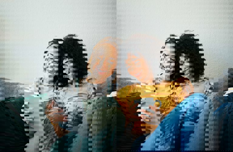 Same sex couple sat on a sofa looking at a tablet Same sex couple sat on a sofa looking at a tablet