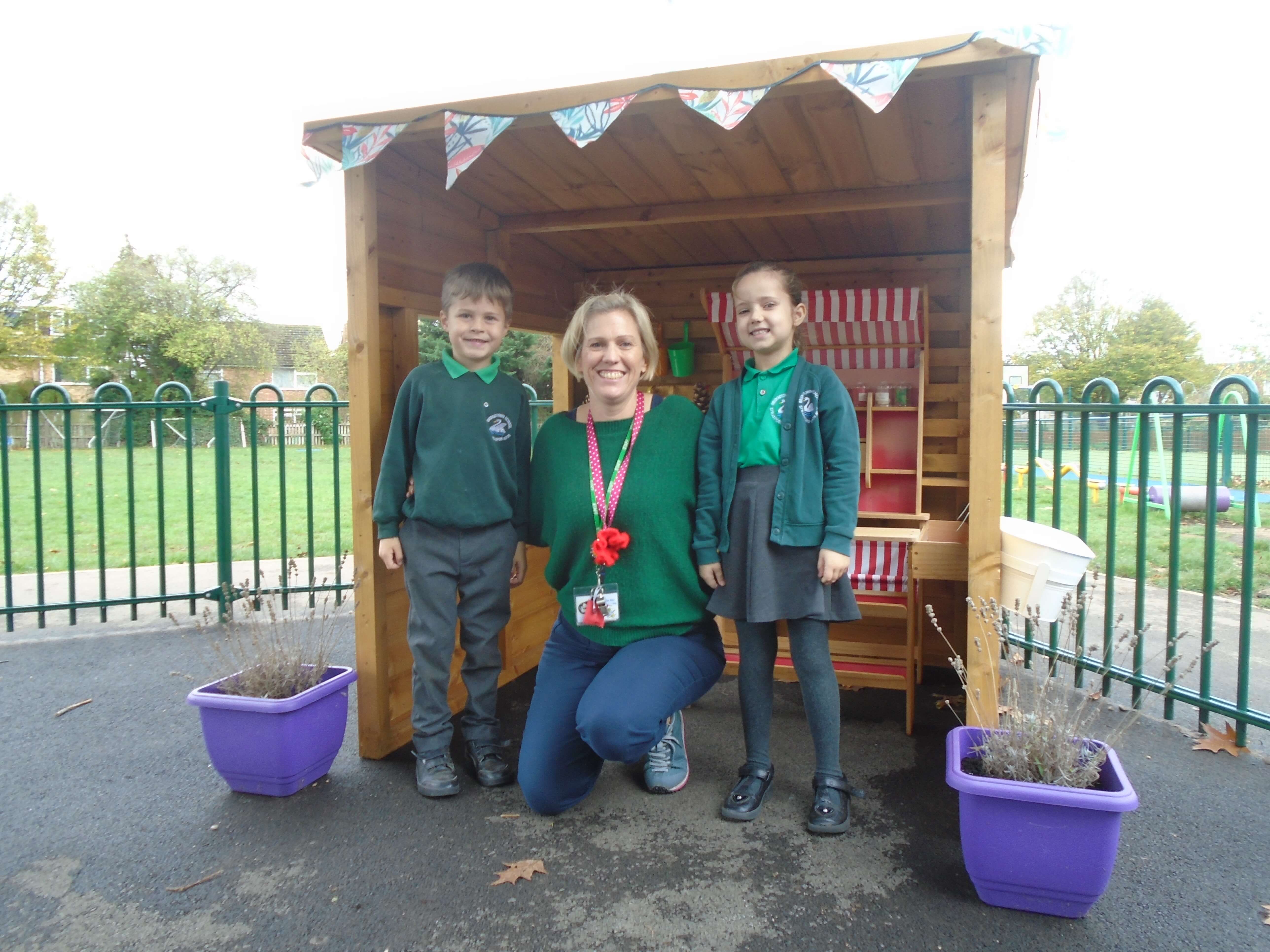three children standing in a wooden shed