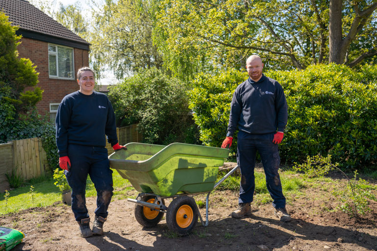 a lady and man standing next to a wheelbarrow a lady and man standing next to a wheelbarrow