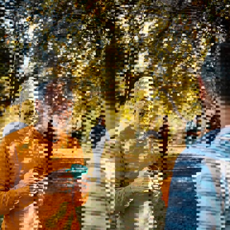 Man in a orange t-shirt smiling in a park talking to his friends Man in a orange t-shirt smiling in a park talking to his friends