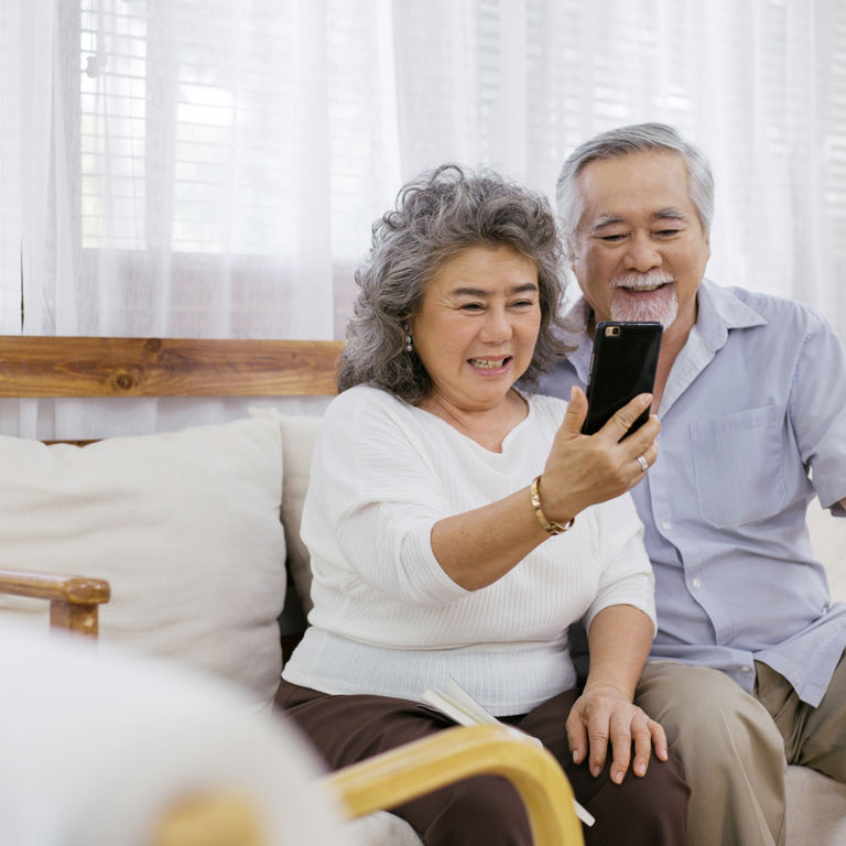 elderly couple sitting on the couch taking a selfie elderly couple sitting on the couch taking a selfie