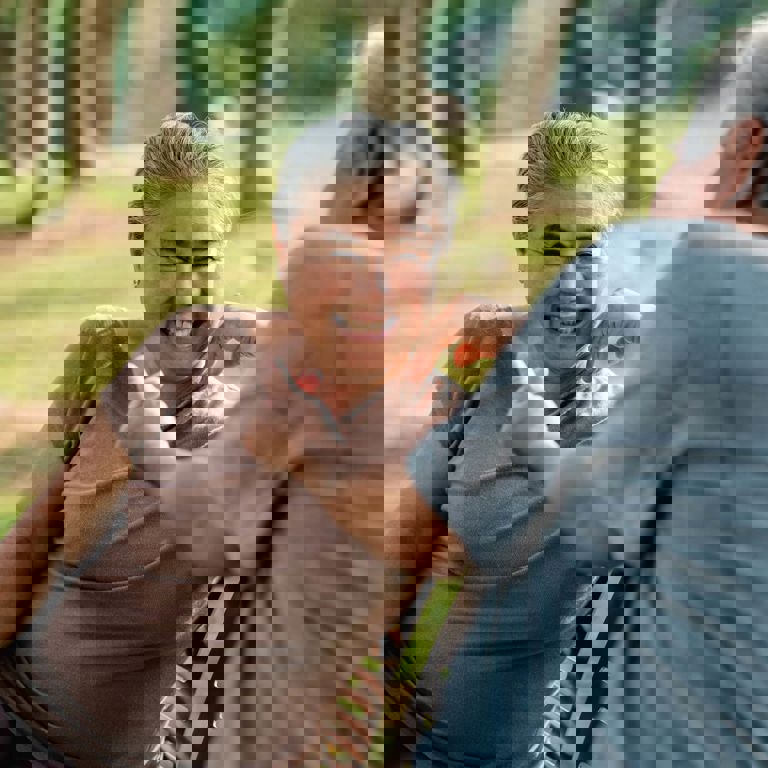 Lady in brown shirt relaxing on bench smiling and chatting to a male friend Lady in brown shirt relaxing on bench smiling and chatting to a male friend