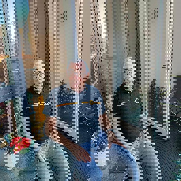 Older gentleman sitting on a chair at the glass table on his house patio Older gentleman sitting on a chair at the glass table on his house patio