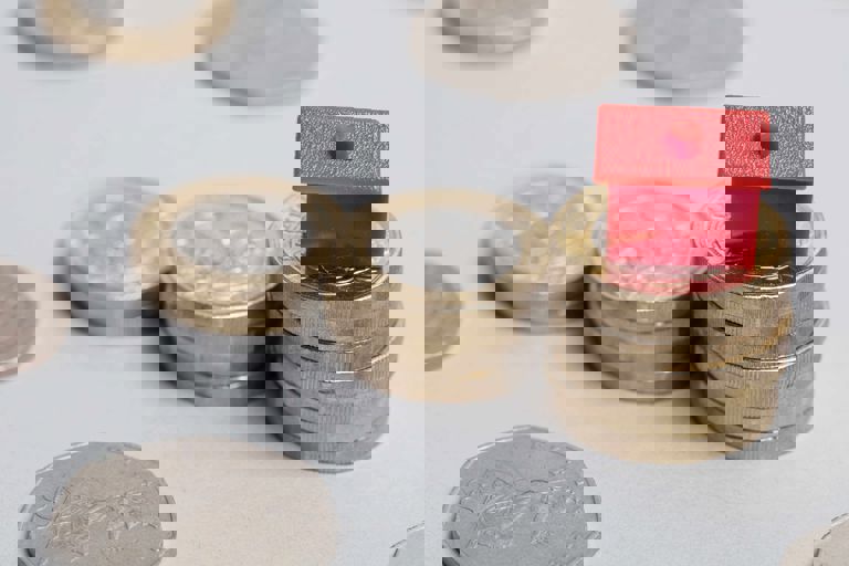 Pound coins stacked with a plastic red house on top Pound coins stacked with a plastic red house on top
