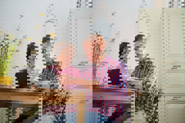 man in checked shirt sitting at a wooden table showing a lady something on a laptop man in checked shirt sitting at a wooden table showing a lady something on a laptop