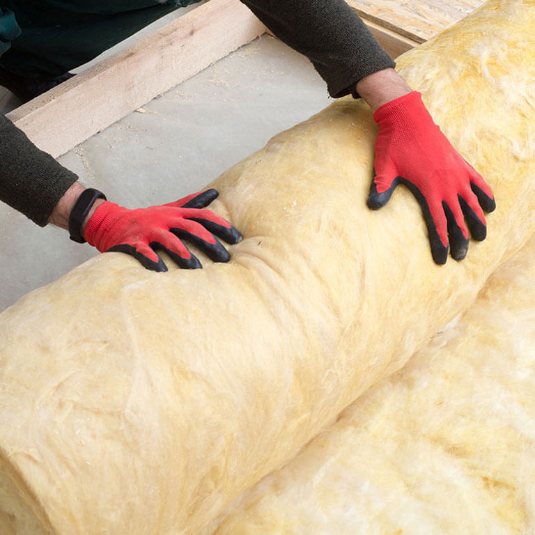two hands with red gloves rolling up insulation padding two hands with red gloves rolling up insulation padding