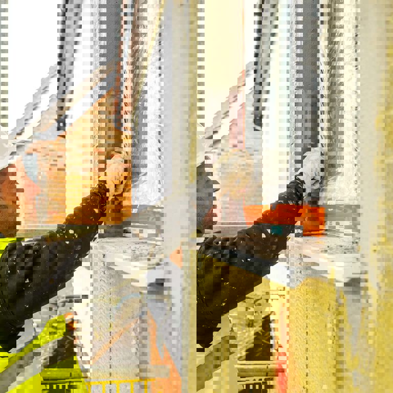 man in yellow reflective shirt insulating a window man in yellow reflective shirt insulating a window