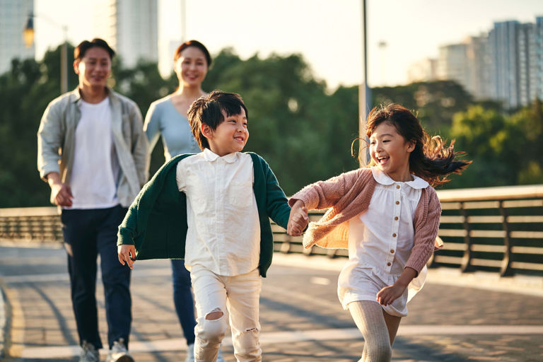 Two children holding hands and walking in front of parents Two children holding hands and walking in front of parents