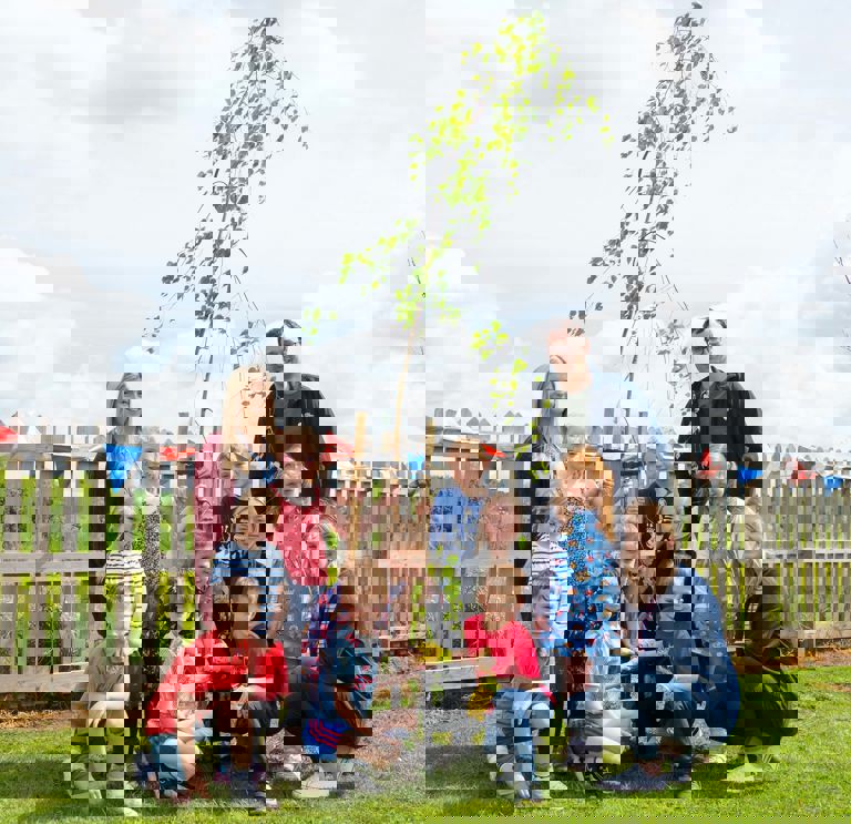 group of children standing in front of a tree they planted group of children standing in front of a tree they planted
