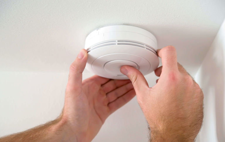 hands installing a carbon monoxide alarm on ceiling hands installing a carbon monoxide alarm on ceiling