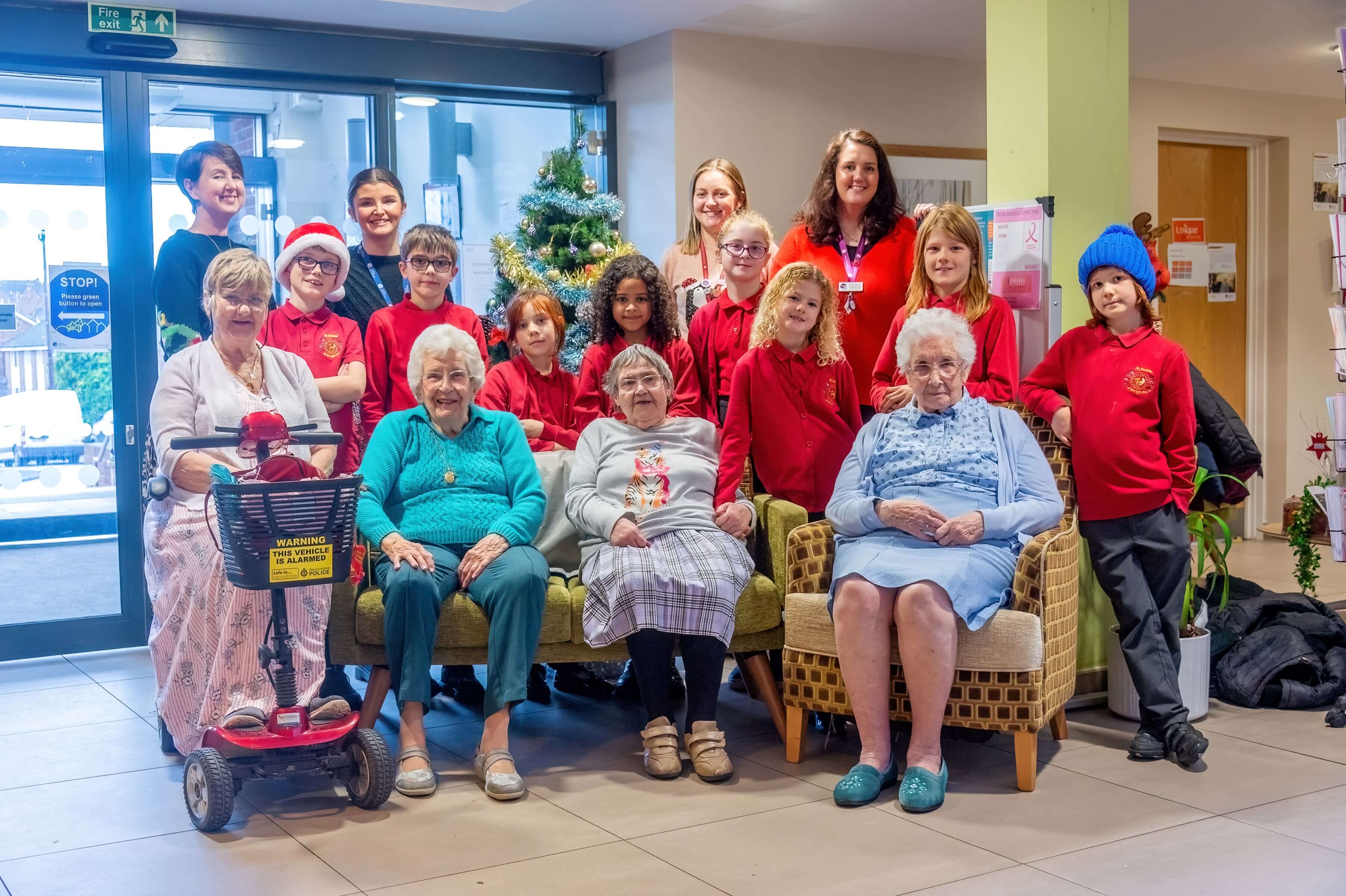 group of children from a choirs wearing red jerseys standing with older women
