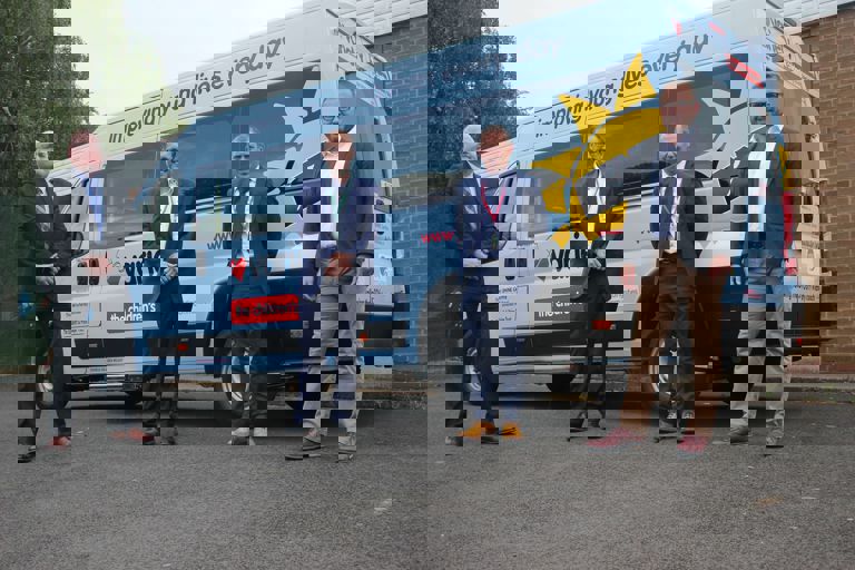 four men standing outside a new coach four men standing outside a new coach