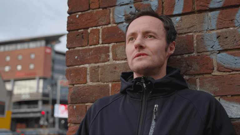 upper body view of a man named Kieran wearing a zipped up black jacket leaning against a brick wall staring into the distance upper body view of a man named Kieran wearing a zipped up black jacket leaning against a brick wall staring into the distance