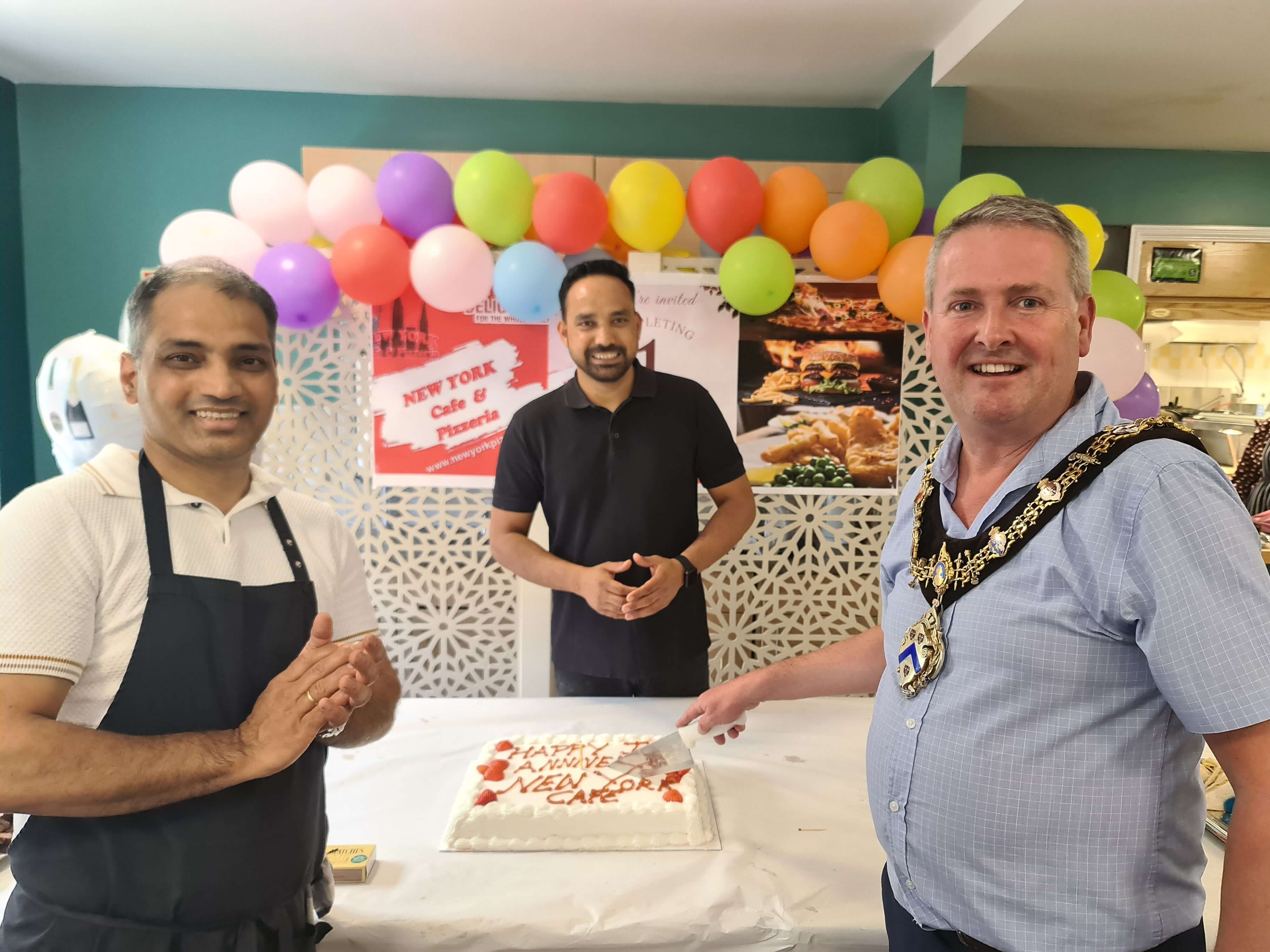 two men standing with the Stratford mayor cutting a cake