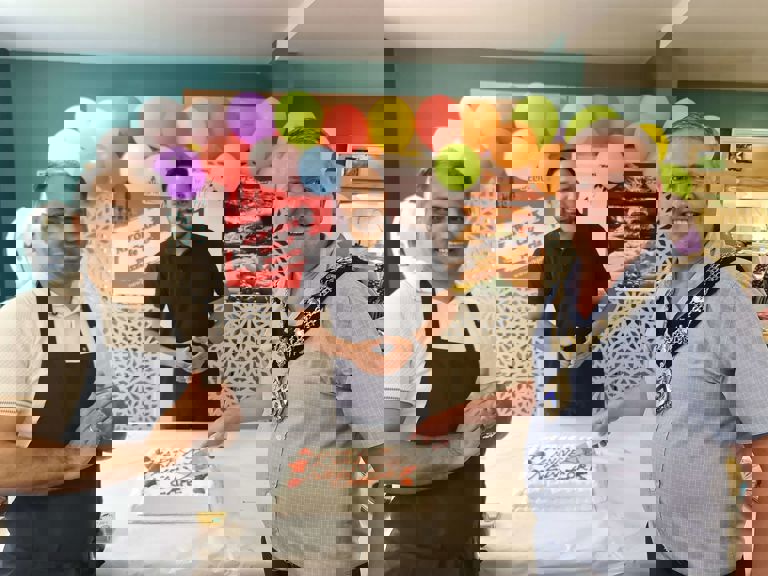 two men standing with the Stratford mayor cutting a cake two men standing with the Stratford mayor cutting a cake