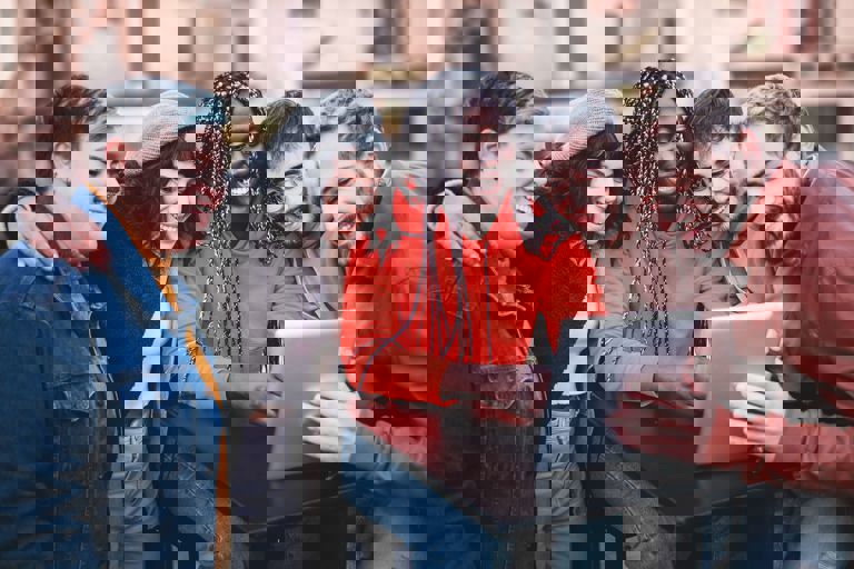 group of friends looking at a tablet and smiling group of friends looking at a tablet and smiling