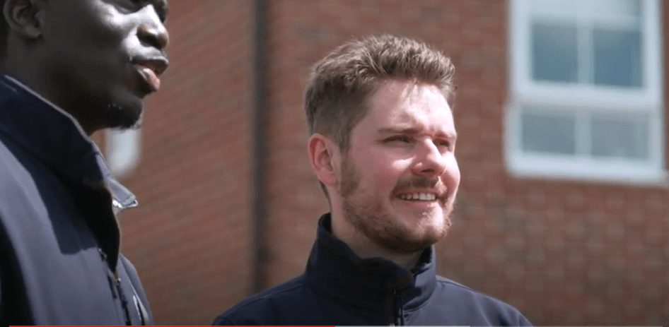 Man standing in front of a brick building smiling