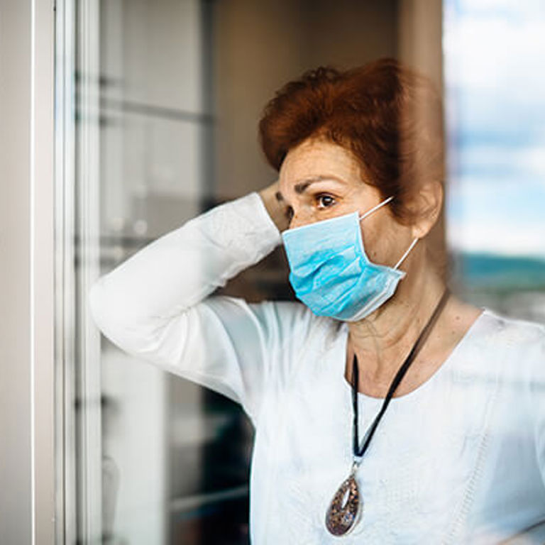 lady standing by window wearing a blue mask lady standing by window wearing a blue mask